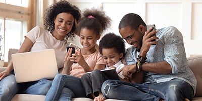 Family looking at laptops and mobile devices.