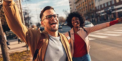 A couple with eyeglasses waving on the street.