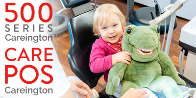 Cute toddler sitting on a dentist chair with a dinosaur doll.